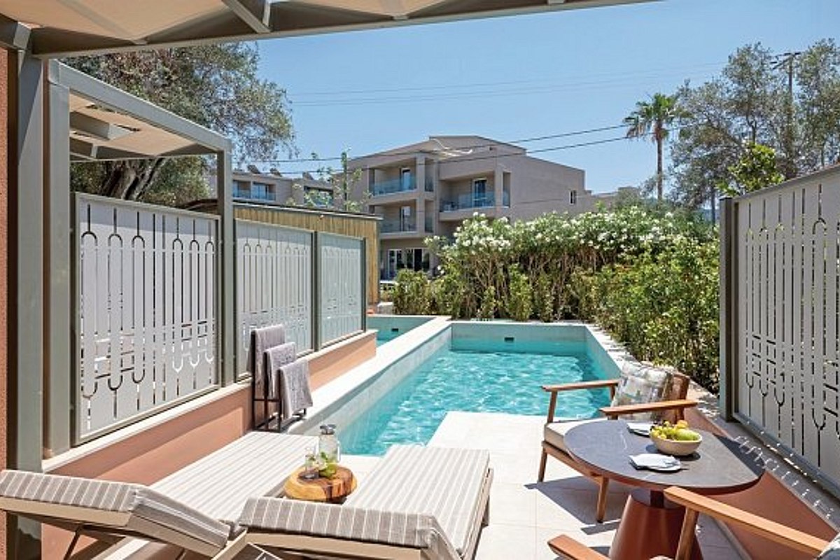 „Moderne Hotelzimmer mit privaten Pools, Terrassen mit Sitzbereichen und gepflegtem Gartenbereich im Vordergrund.“