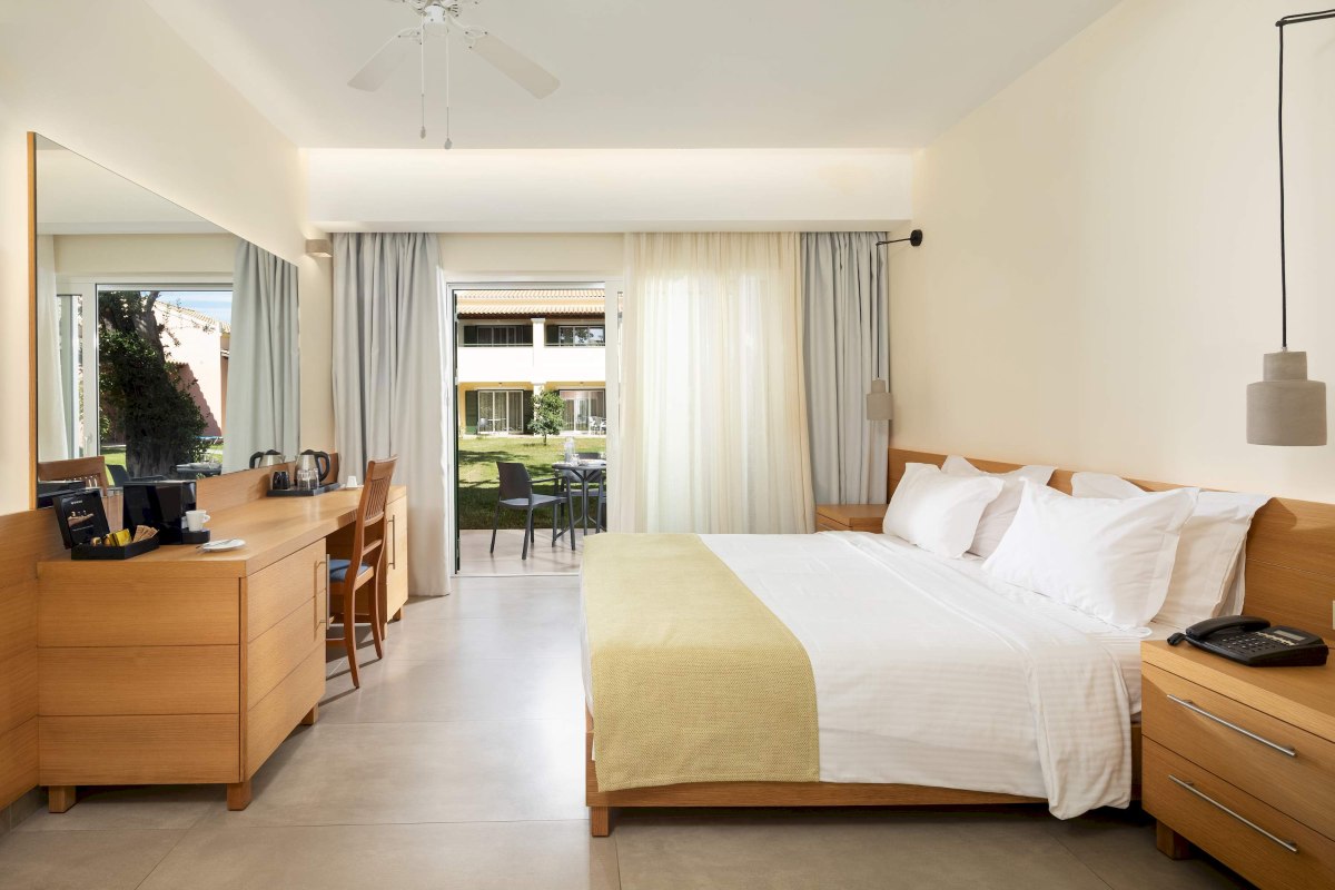 Helles Zimmer mit Twinbett, Nachttischen und offenem Fenster zum möbliertem Balkon.