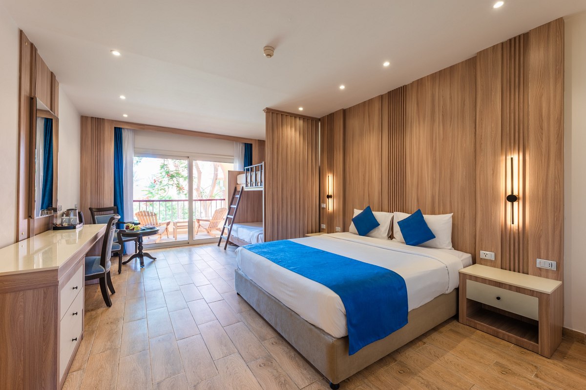 Familienfreundliches Hotelzimmer mit Doppelbett, Etagenbett, Schreibtisch, Holzboden und Balkon mit Blick ins Grüne.