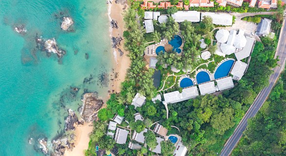 Luftaufnahme des Sentido Khao Laks am Strand mit türkisfarbenem Wasser, mehreren Pools und grüner Vegetation.