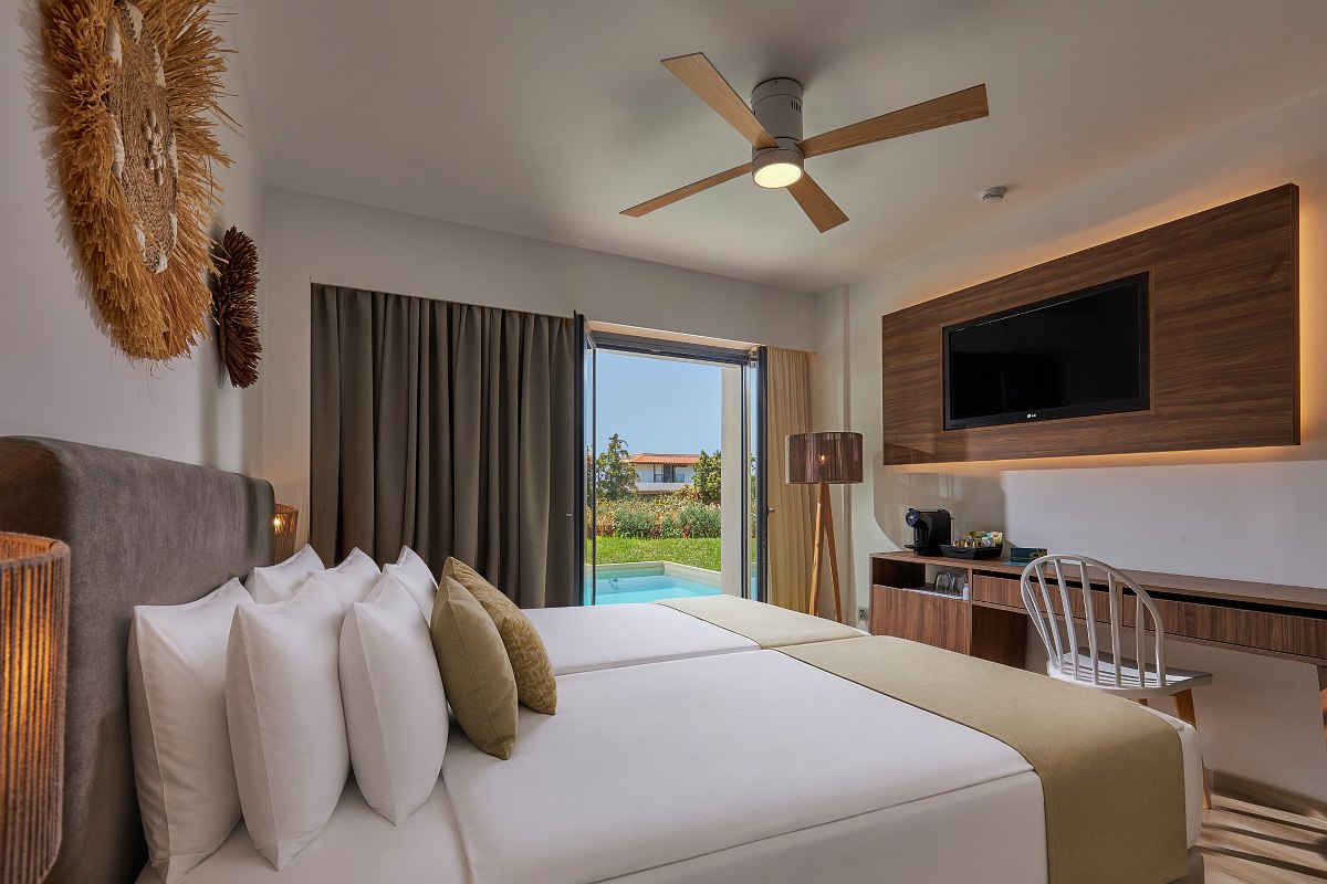 Modernes Hotelzimmer mit Doppelbett, Holzdetails, Schreibtisch, Sofa und direktem Zugang zum privaten Pool.