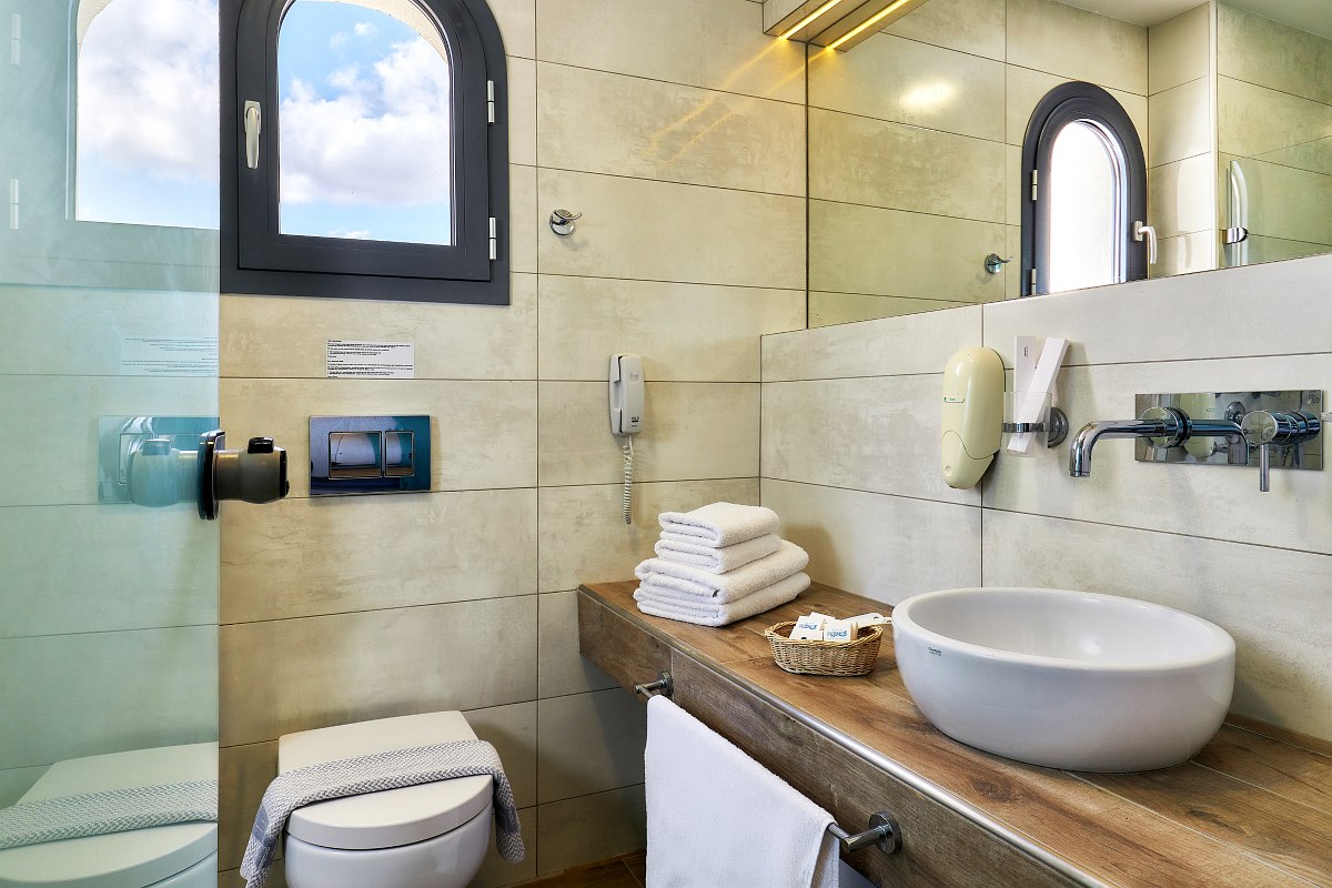 Modernes Badezimmer mit großer begehbarer Regendusche, beleuchtetem Spiegel, Waschbecken und Holzoptik-Fliesen.