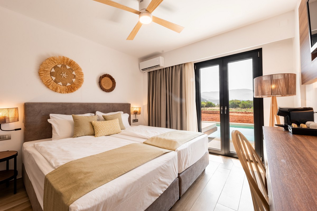 Modernes Hotelzimmer mit Doppelbett, Naturdeko, Schreibtisch und Zugang zur Terrasse mit privatem Pool.