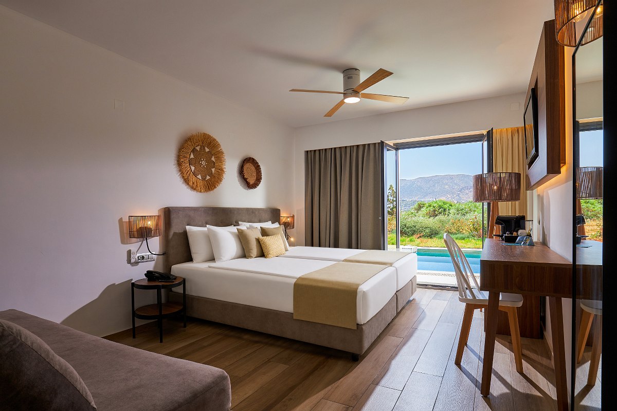 Modernes Hotelzimmer mit Doppelbett, Naturdeko, Schreibtisch und Zugang zur Terrasse mit privatem Pool.