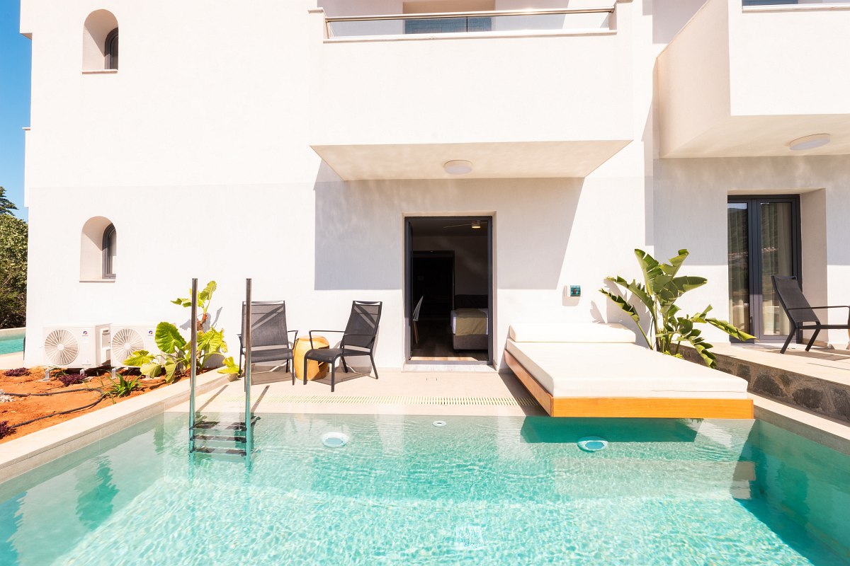 Hotelzimmer mit direktem Zugang zum privaten Pool, Sonnenliegen, Pflanzen und Sitzbereich auf der Terrasse.