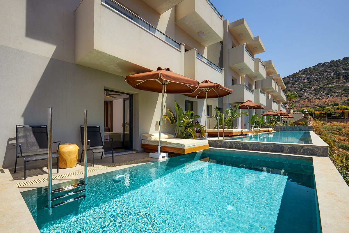 Hotelzimmer mit direktem Zugang zum privaten Pool, Sonnenliegen, Pflanzen und Sitzbereich auf der Terrasse.