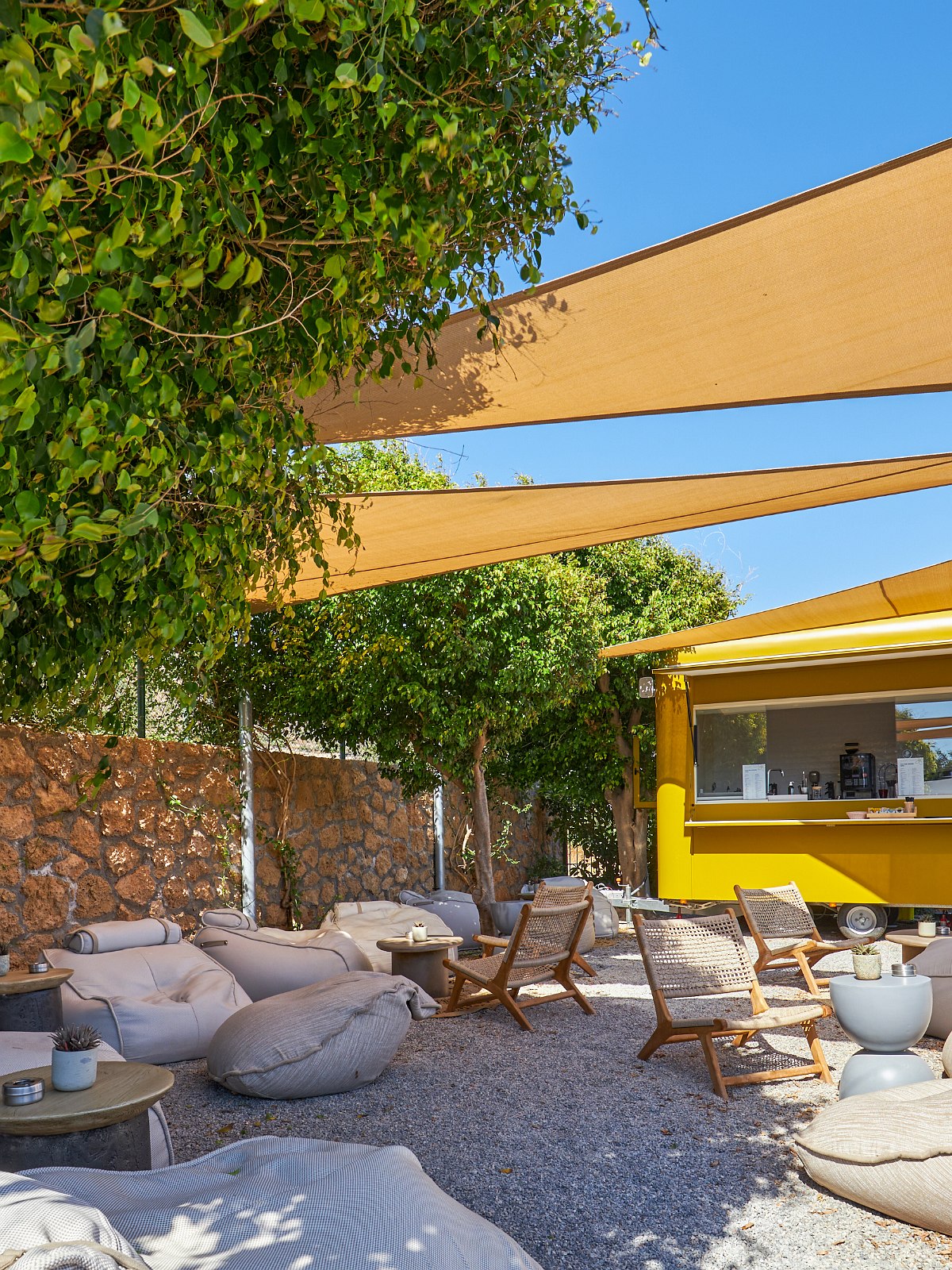 Elegant gedeckter Tisch im Außenbereich eines Restaurants mit Blick auf Palmen, Pool und Lounge-Bereich im Hintergrund.