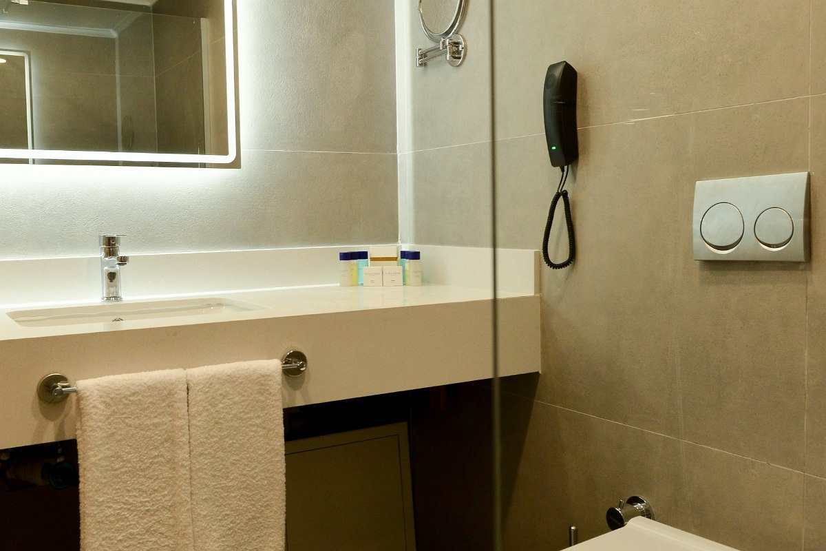 Modernes Hotelbad mit Glasdusche, edlem Marmorwaschtisch und hochwertigen Pflegeprodukten.