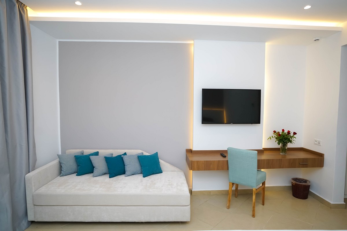 Moderner Wohnbereich mit TV, Schreibtisch, gemütlichem Sofa und minimalistischer Wanddeko.