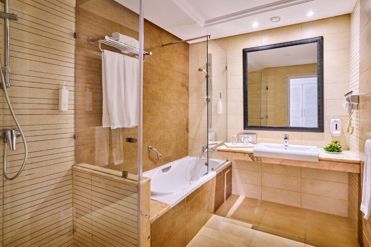 Modernes Hotel Wohnzimmer mit bequemer grauer Couch, rundem Esstisch und blauen Stühlen, hellem Marmorboden und minimalistischer Einrichtung.