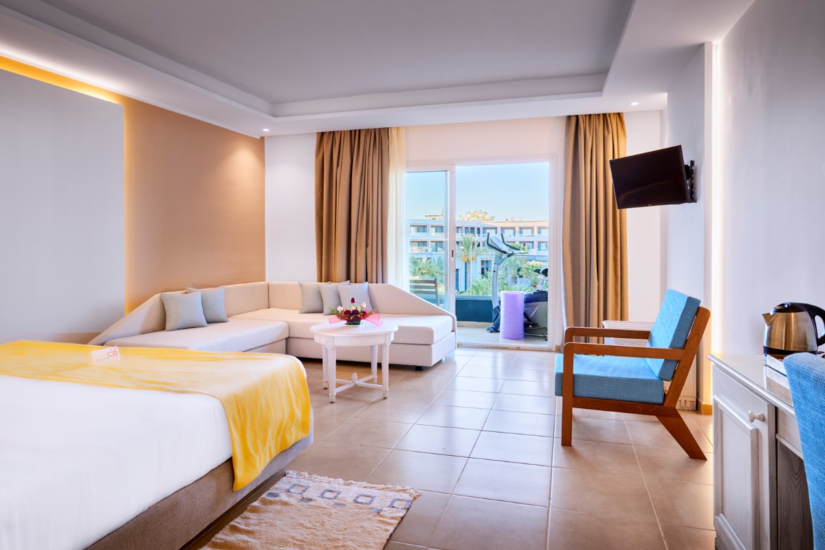 Modernes Hotelzimmer mit Doppelbett, Fitnessrad und Holz-Gymnastikwand, hell und stilvoll eingerichtet.