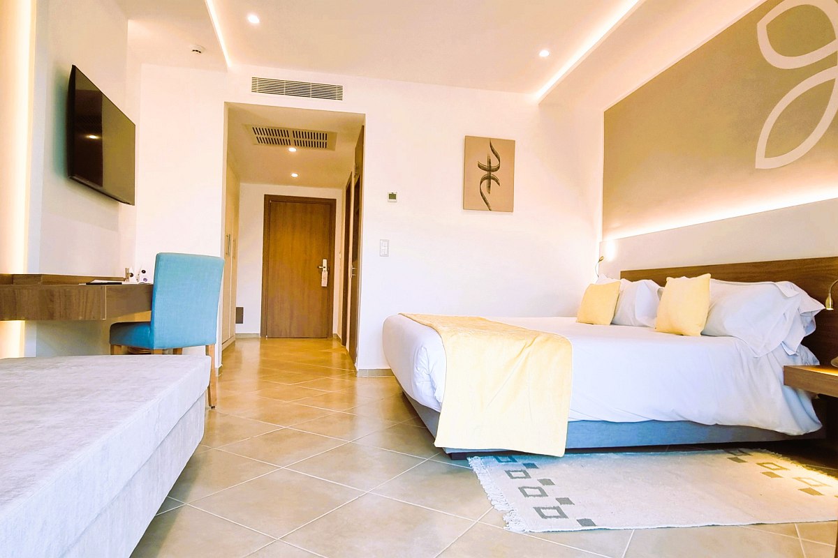 Modernes Hotelzimmer mit großem Doppelbett, hellem Marmorboden, Sitzbereich und Zugang zu privatem Pool im Garten.