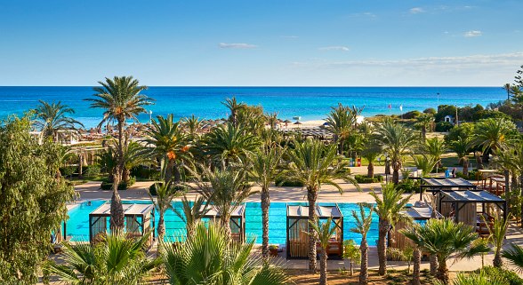 Modernes Hotellobby mit hellen Marmorböden, stilvollen Sofas und dekorativer Trennwand im arabischen Design.