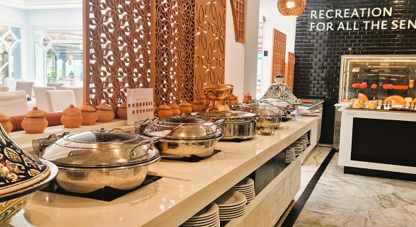 Modernes, helles Hotelrestaurant mit weißen Marmorfliesen, dekorativen Wänden und vielen Sitzgelegenheiten.