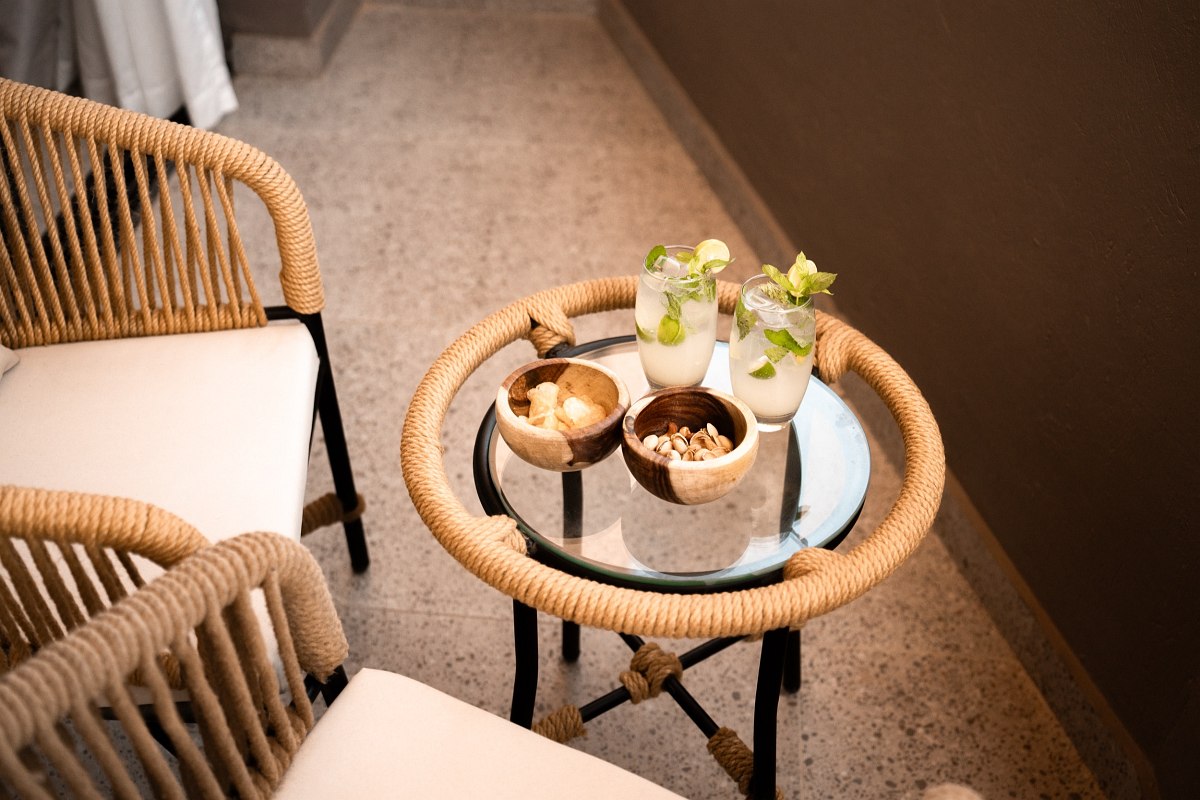 „Möblierter Balkon mit zwei Rattanstühlen, kleinem Glastisch und Vorhang-Schiebetür in modernem Design.“