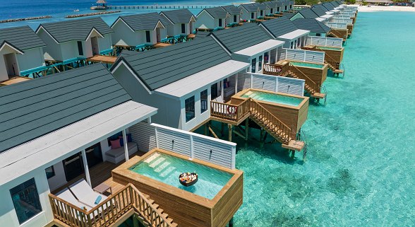 Reihe von modernen Wasserbungalows mit privaten Holzterrassen und kleinen Pools über klarem, türkisfarbenem Wasser.