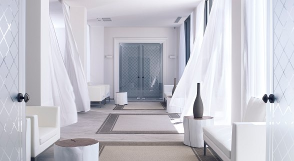 Heller, minimalistischer Spa- oder Ruhebereich mit weißen Möbeln, wehendem Vorhang, dezenten Deko-Elementen und viel Tageslicht.