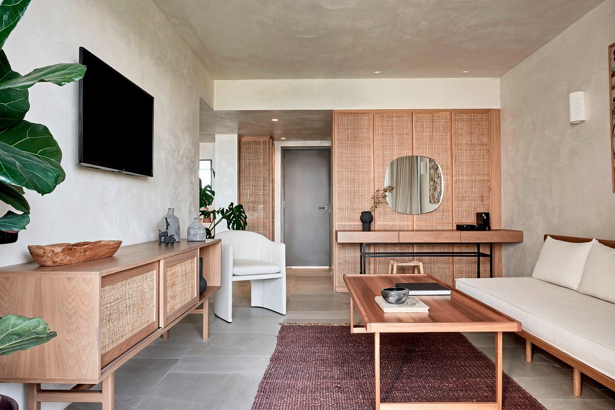 Modern eingerichtetes Wohnzimmer mit Naturholz-Möbeln, Wandspiegel und gemütlichem Sofa in heller, luftiger Atmosphäre.
