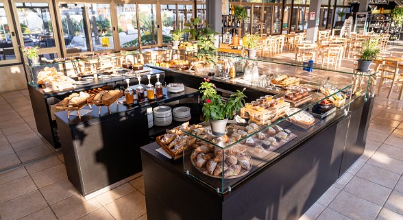 Großzügiges Frühstücksbuffet mit vielfältiger Auswahl an Backwaren, Marmeladen und frischen Speisen in hellem, modernem Restaurant.
