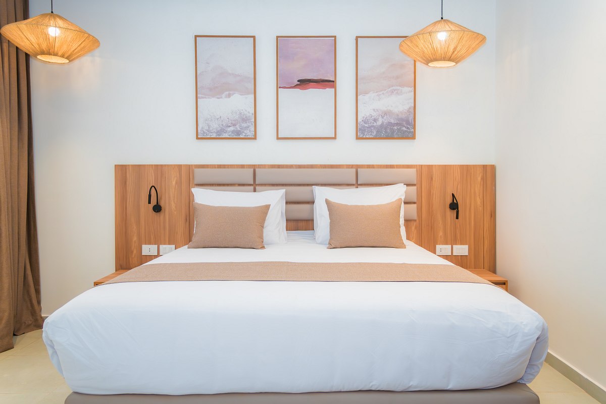 Modernes Hotelzimmer mit Doppelbett, blauen Akzenten, gewölbter Ziegeldecke und Balkon mit Blick auf die Hotelanlage.