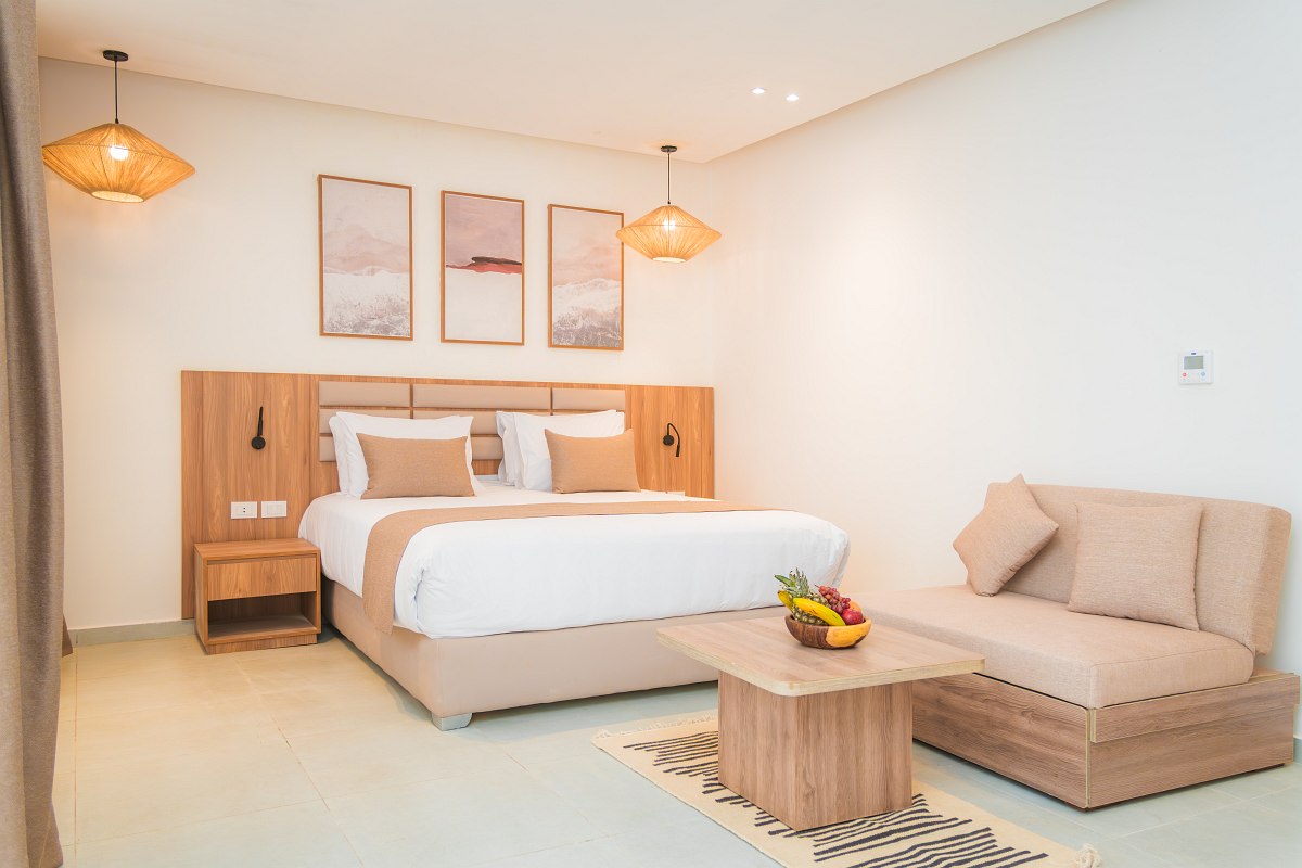 Heller Wohnbereich mit großer Eckcouch, Holzdekor, TV, gewölbter Ziegeldecke und modernem Interieur in warmen Tönen.