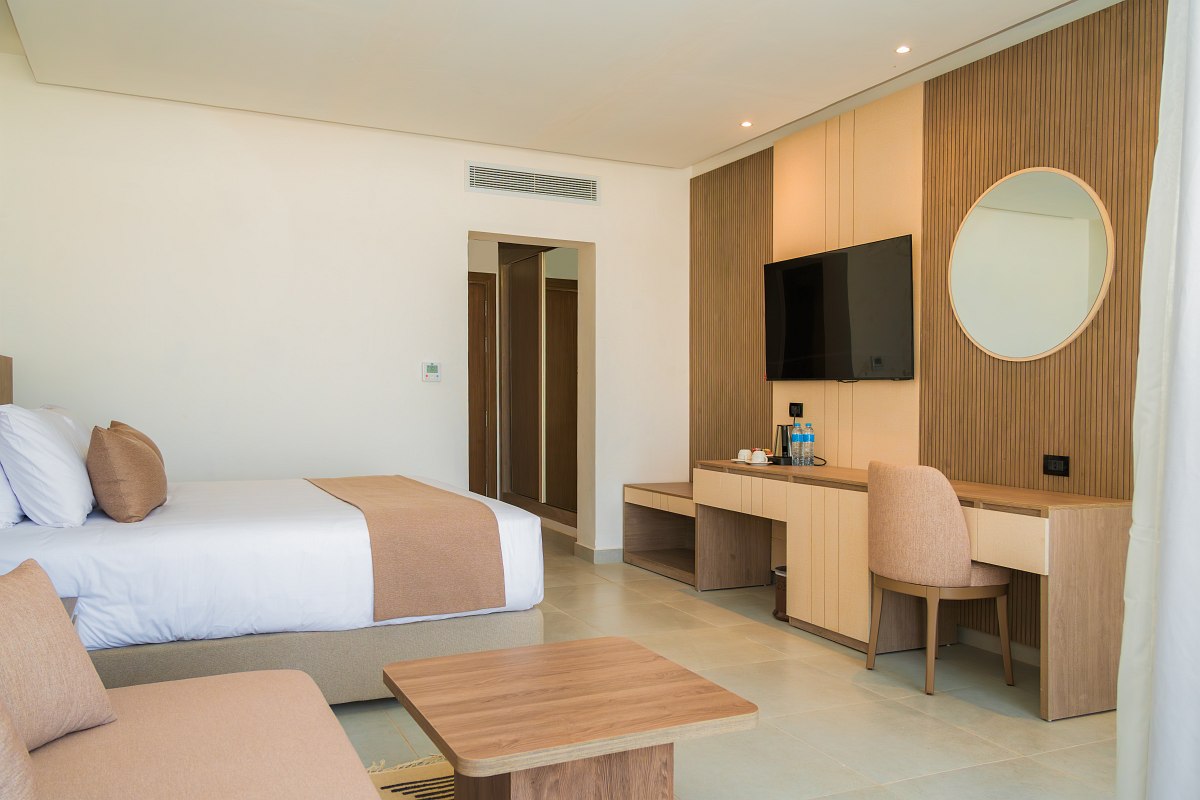 Heller Wohnbereich mit großer Eckcouch, Holzdekor, TV, gewölbter Ziegeldecke und modernem Interieur in warmen Tönen.