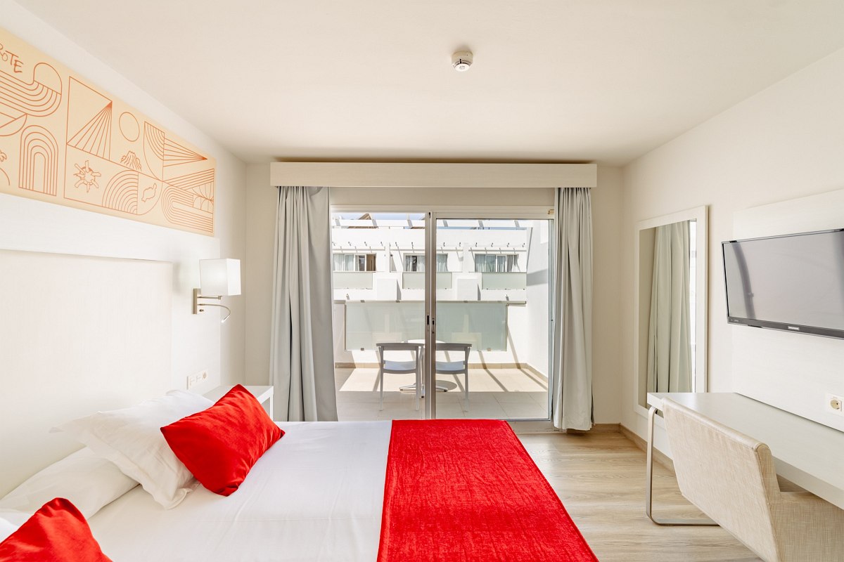 Bright hotel room with double bed, desk, flat-screen TV, coffee machine and balcony with natural light.