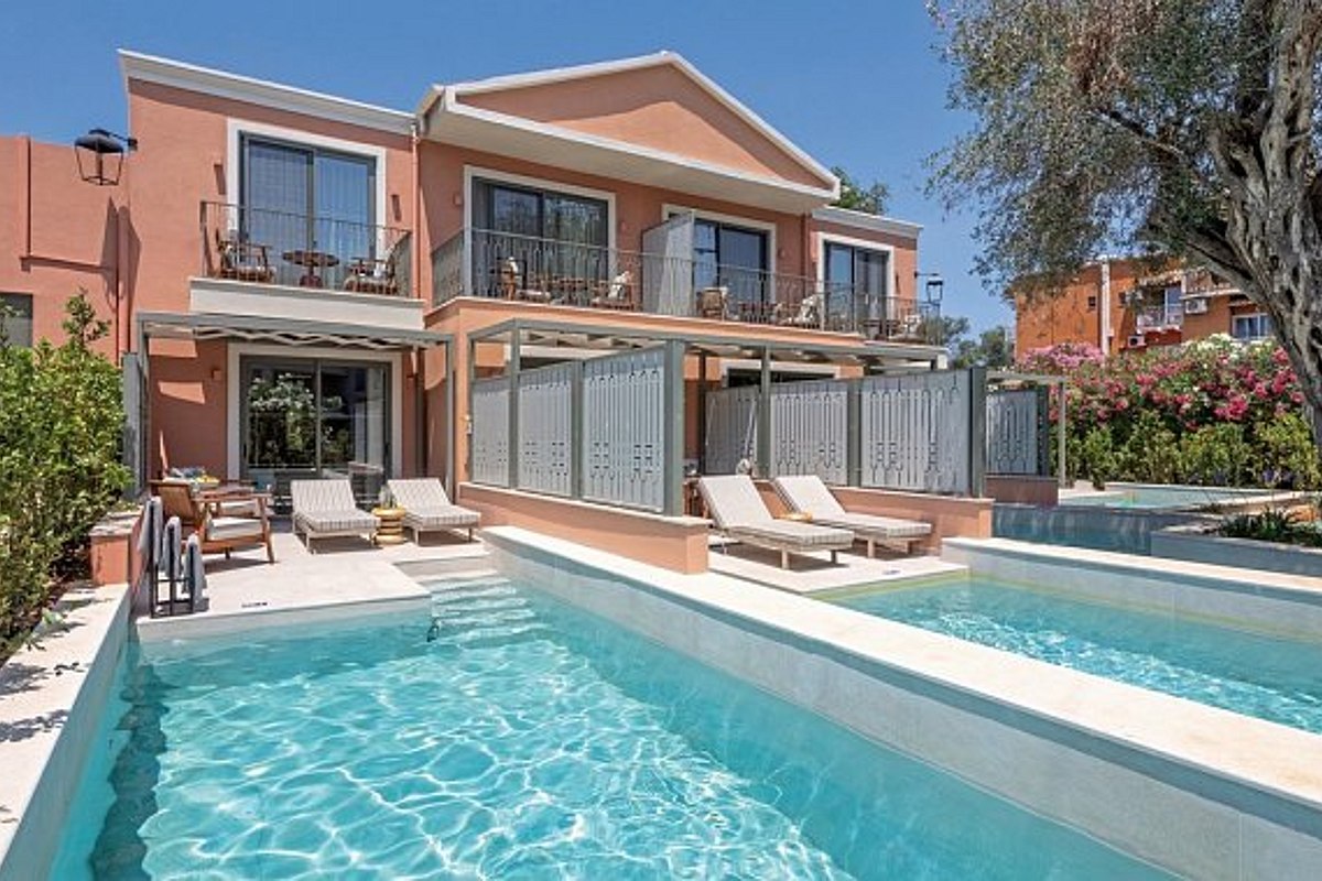 Two ground-floor apartments with private terraces and plunge pools. Each terrace has outdoor furniture, greenery, and steps leading down to a grassy area. The building is painted a warm peach color.