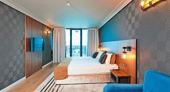 Superior room at Sentido Bellevue Beach: Modern hotel room with two beds, blue armchair, TV and balcony with sea view.
