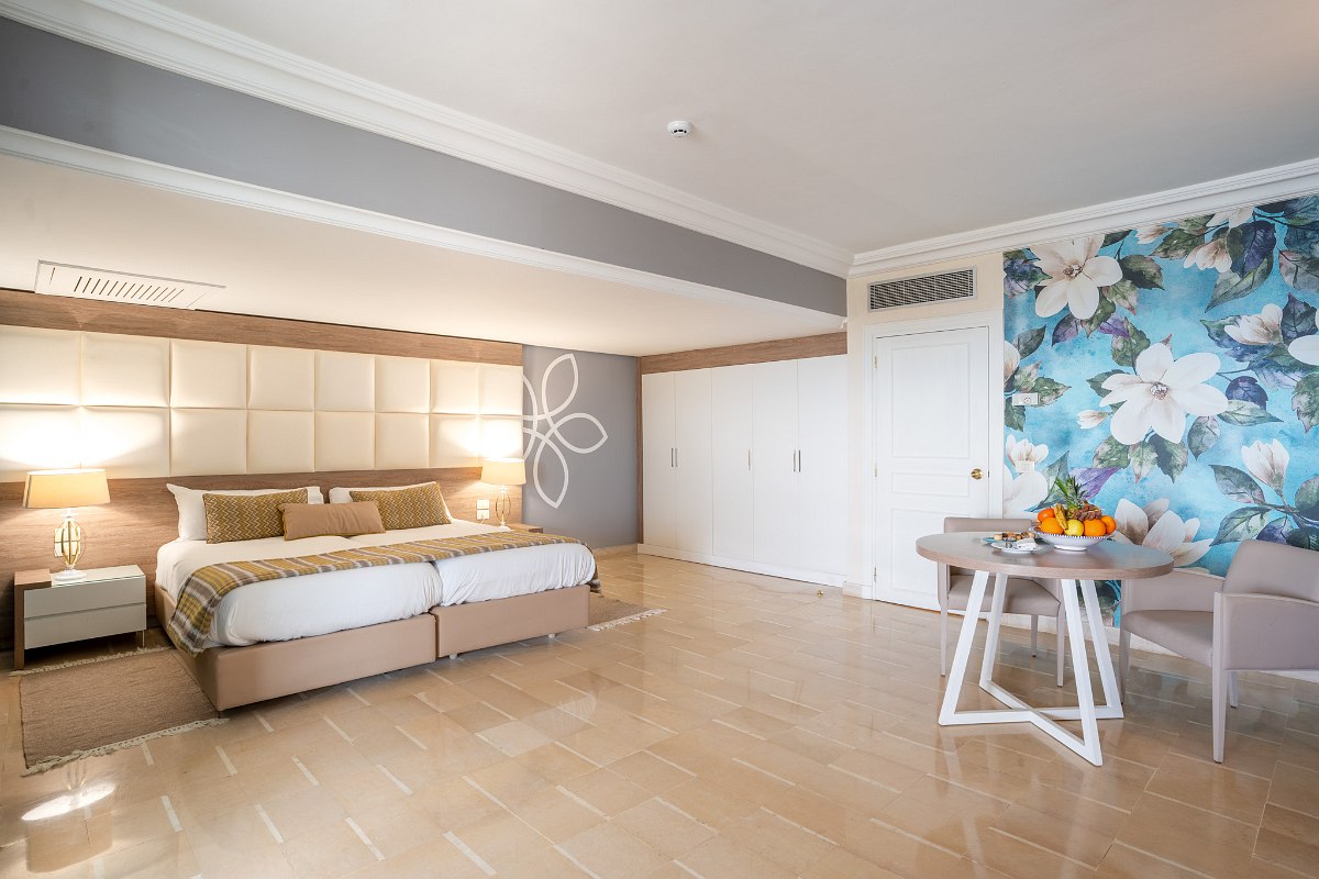 Modern hotel room with double bed, large closets, seating area and eye-catching flower wall.