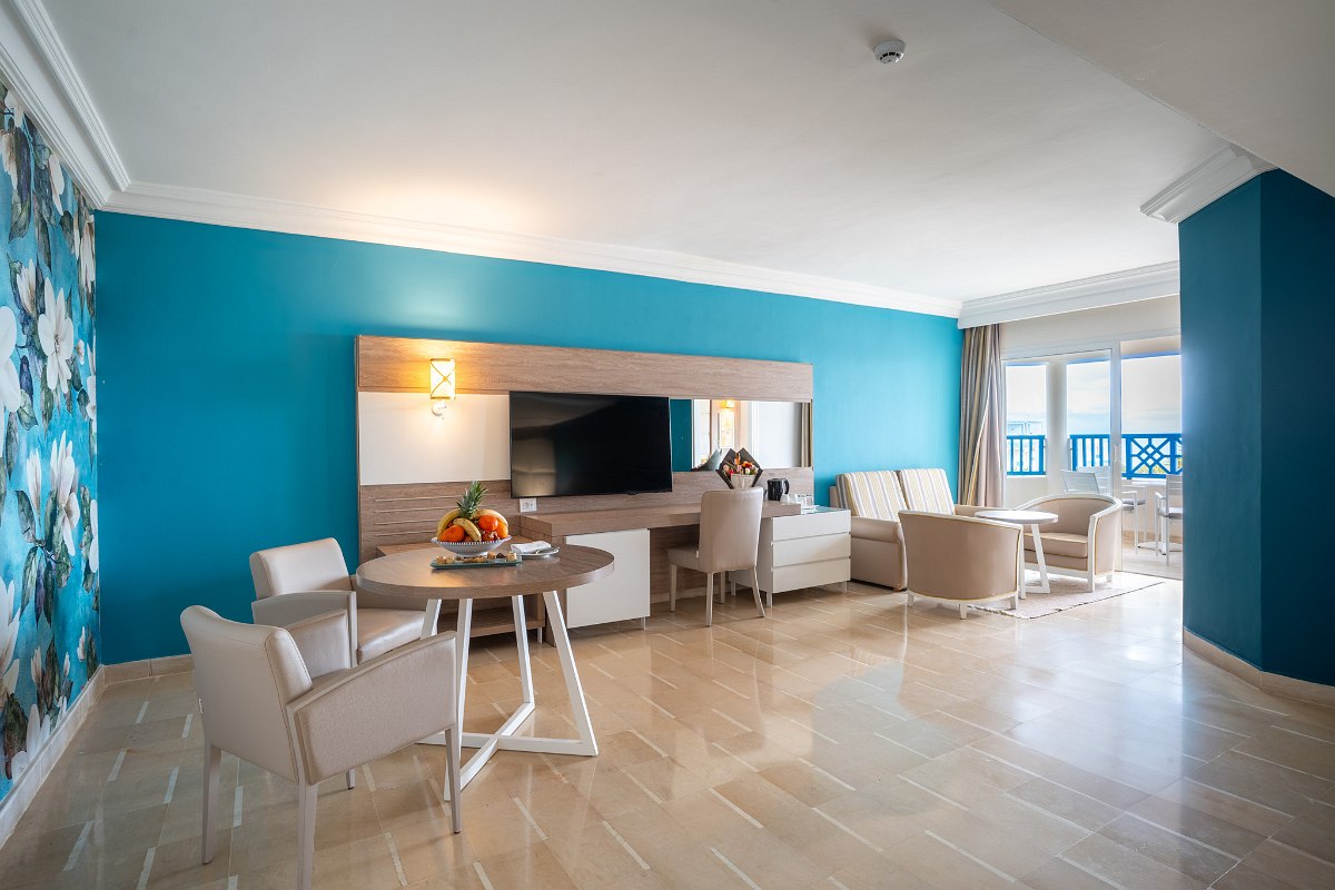 Modern hotel room with double bed, large closets, seating area and eye-catching flower wall.