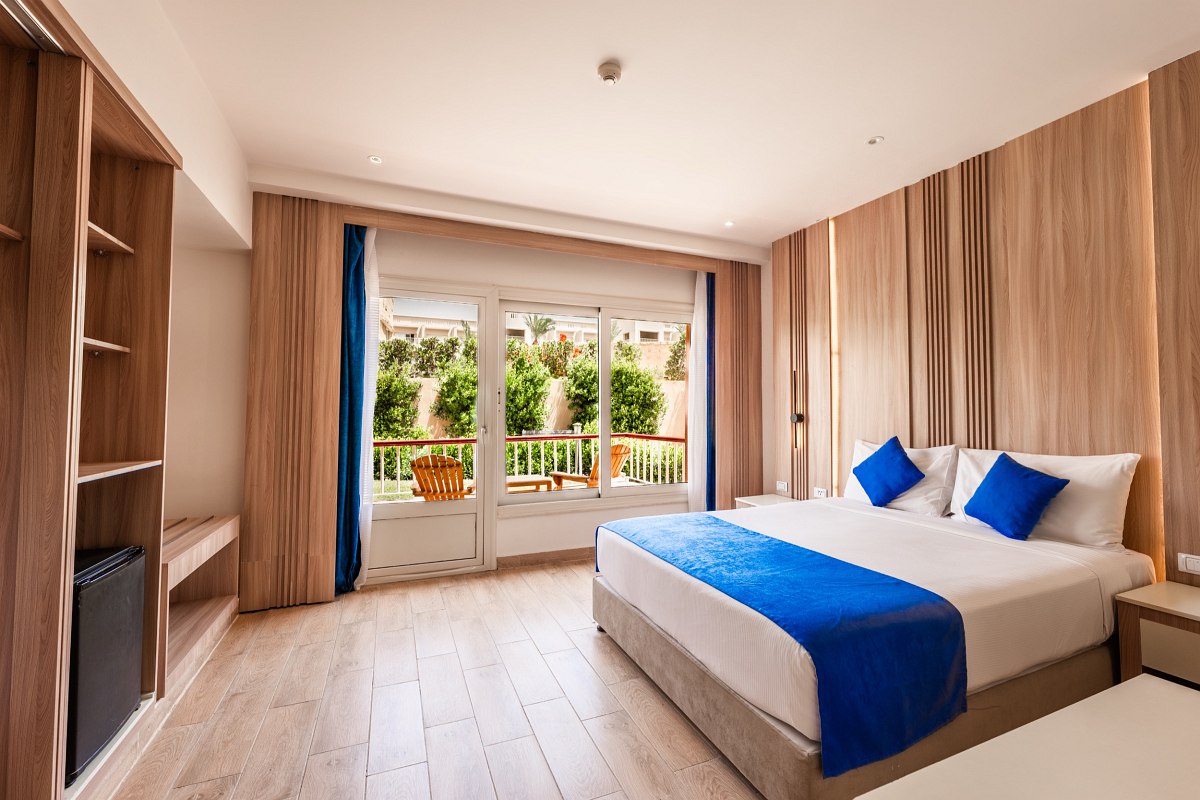 Bright room with two single beds, wood floors, and large windows with garden views. Simple and cozy.