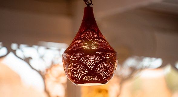 Ornate, perforated hanging lantern casting warm light, creating intricate patterns on nearby surfaces.