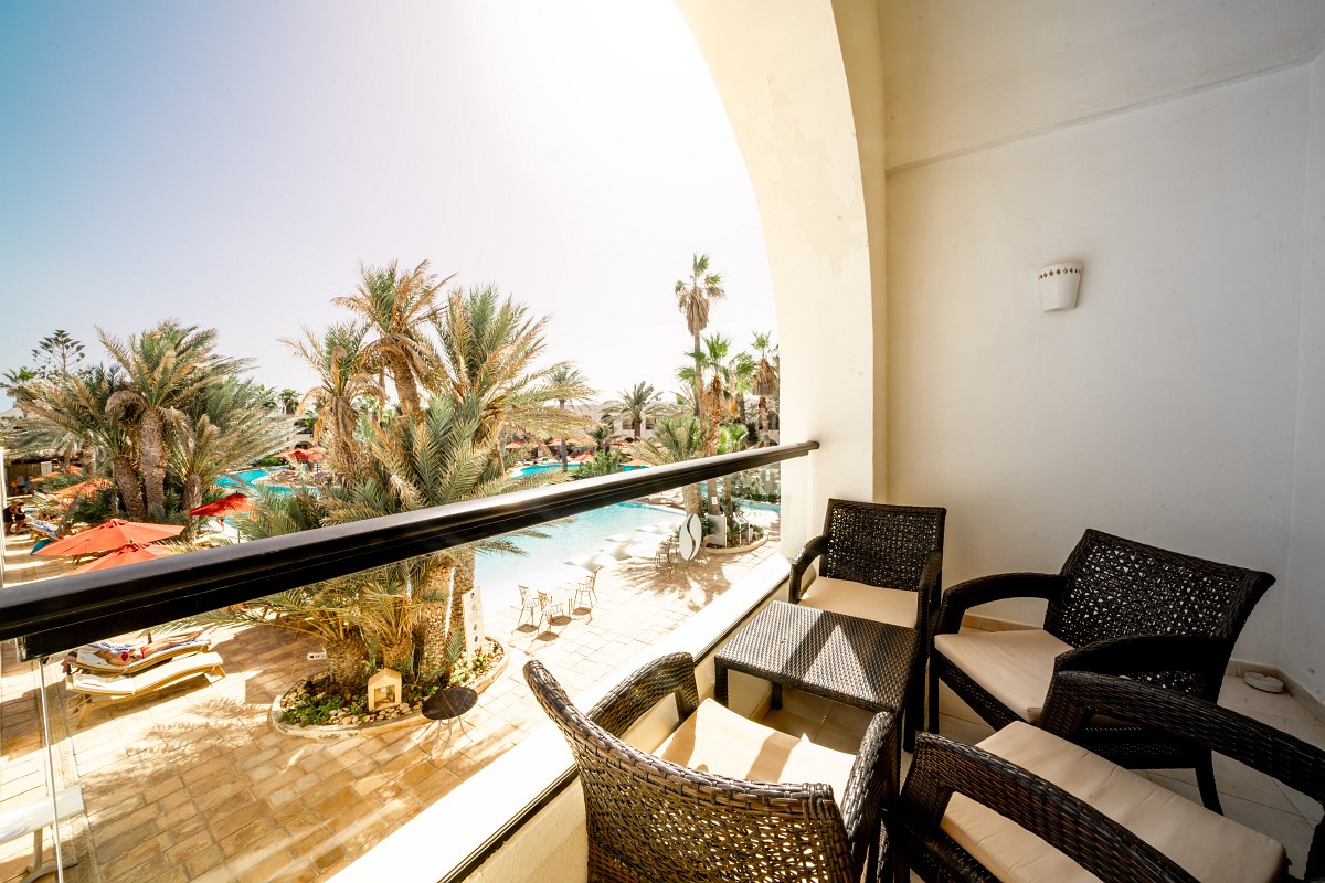 Cozy terrace with wicker chairs, view of green plants, bright and inviting.