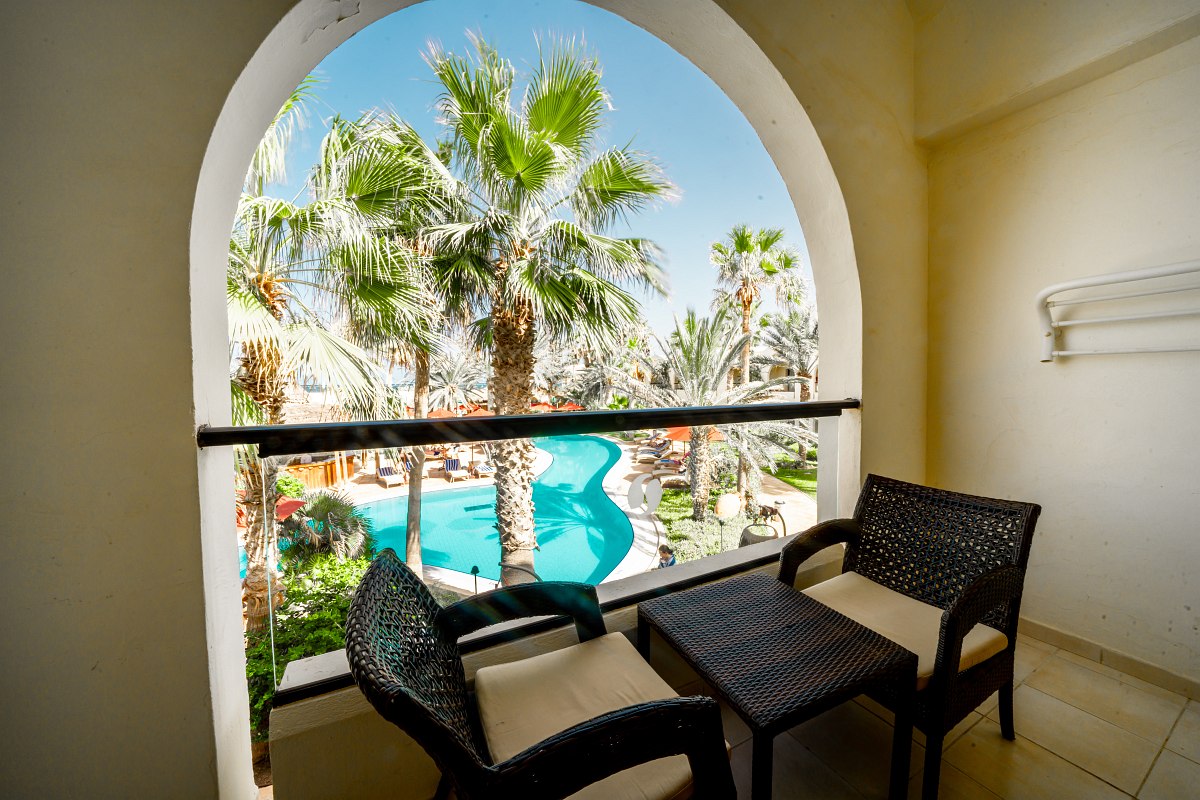 Bright room with balcony, pool view and cozy seating area, ideal for relaxing.