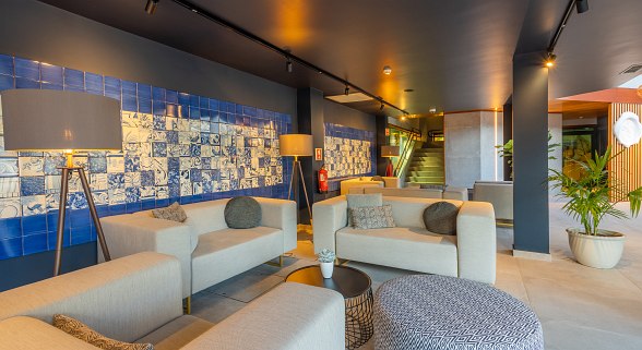 Modern hotel lobby with cozy sofas, stylish lamps and blue azulejo tiles on the wall.