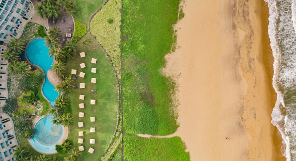 Drone shot of the Sentido Heritance Negombo hotel with pools, sun loungers on the lawn and direct access to the extensive sandy beach and sea.