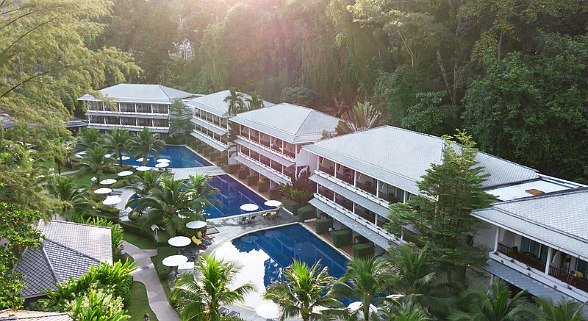 Aerial view of the tropical resort Sentido Khao Lak with several buildings, swimming pools, palm trees and sun loungers in the green jungle.