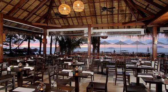  Terrace restaurant of Hotel Sentido Khao Lak with covered tables, parasols and sea views at sunset.