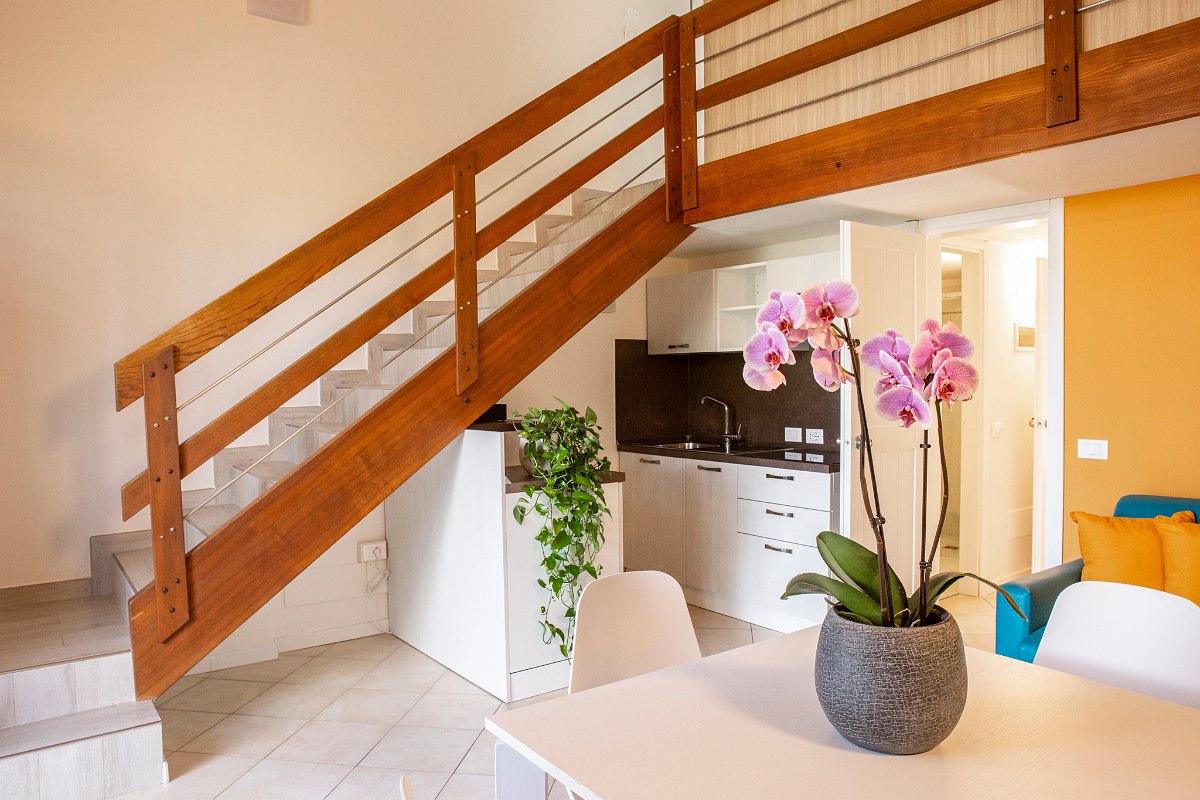  Modern apartment with kitchen, dining table, wooden staircase to the gallery and colorful accents in a friendly atmosphere.