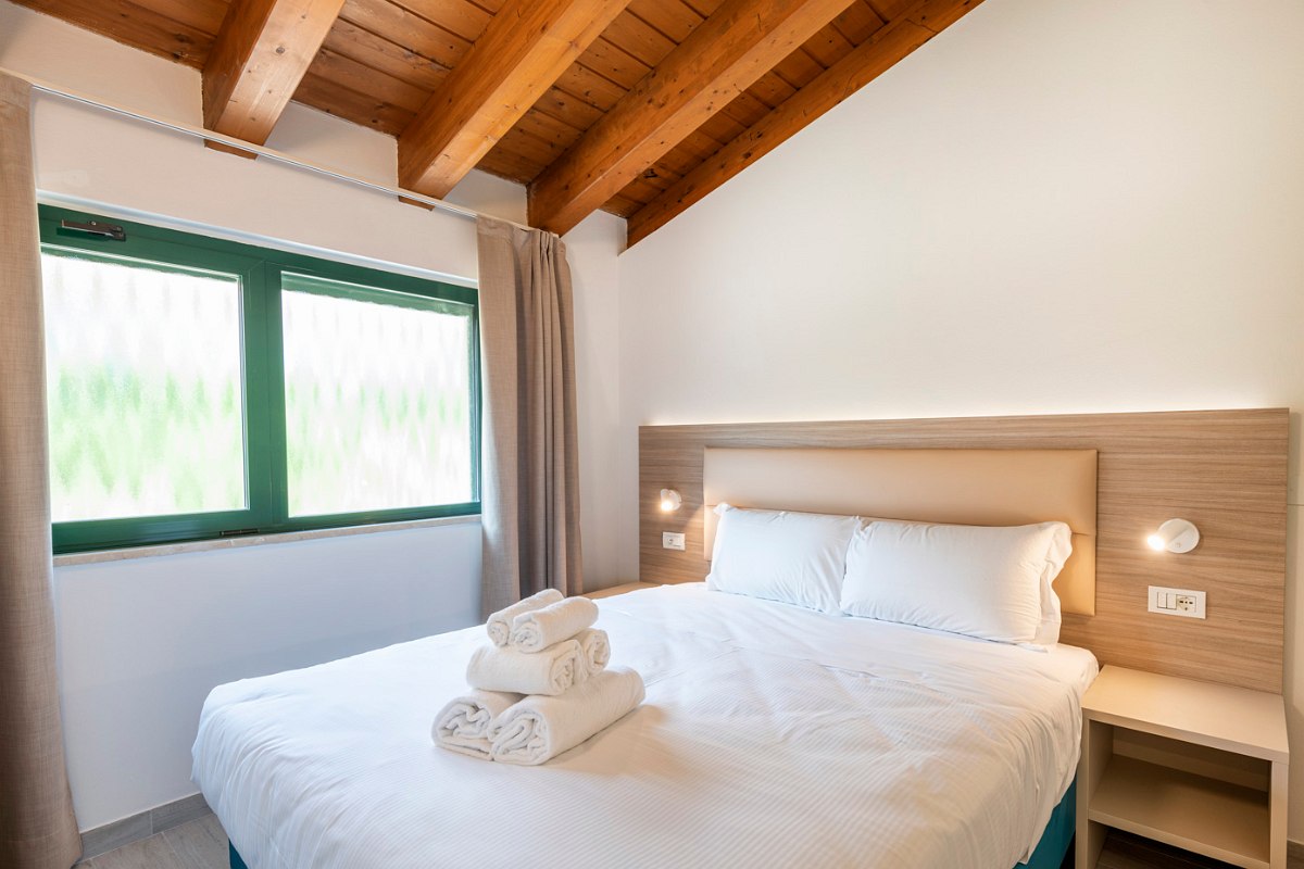 Cozy second bedroom with double bed, wooden ceiling and large window for plenty of natural light and fresh air.