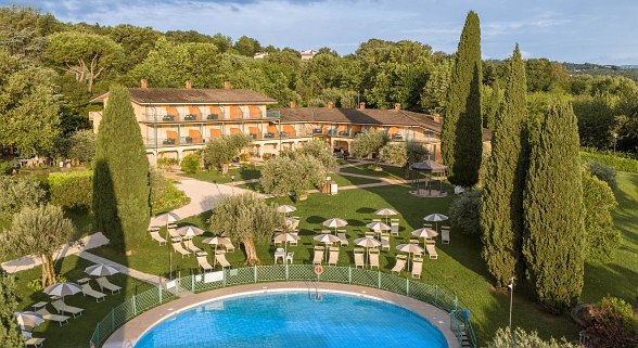 Spacious hotel complex of Sentido Lago di Garda Premium Village with pool, sun loungers, parasols and well-kept garden in quiet, green surroundings.