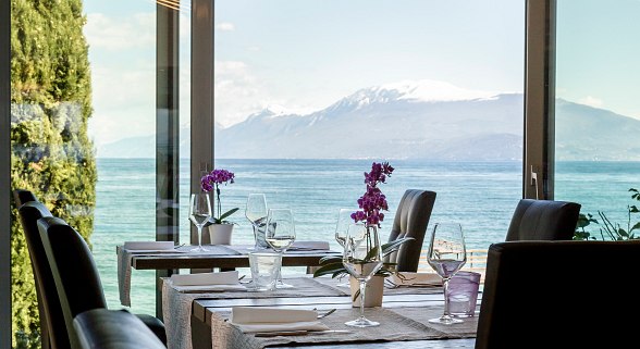 Elegantly decorated restaurant area with large windows and panoramic views of the lake and snow-capped mountains.