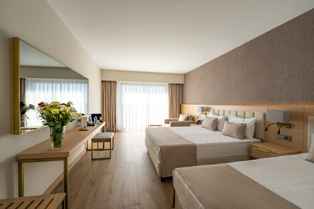 Elegant hotel room with two beds, stylish interior and balcony with fantastic sea view at dusk.