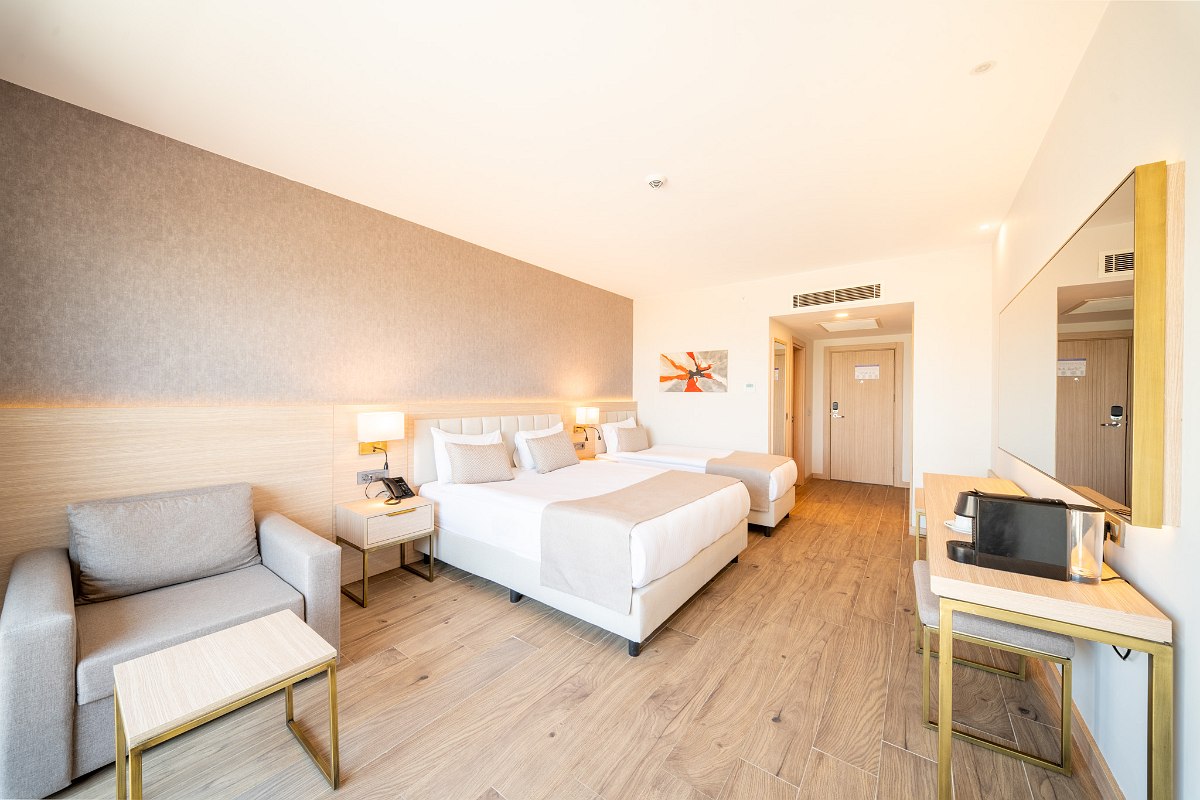 Elegant hotel room with two beds, stylish interior and balcony with fantastic sea view at dusk.