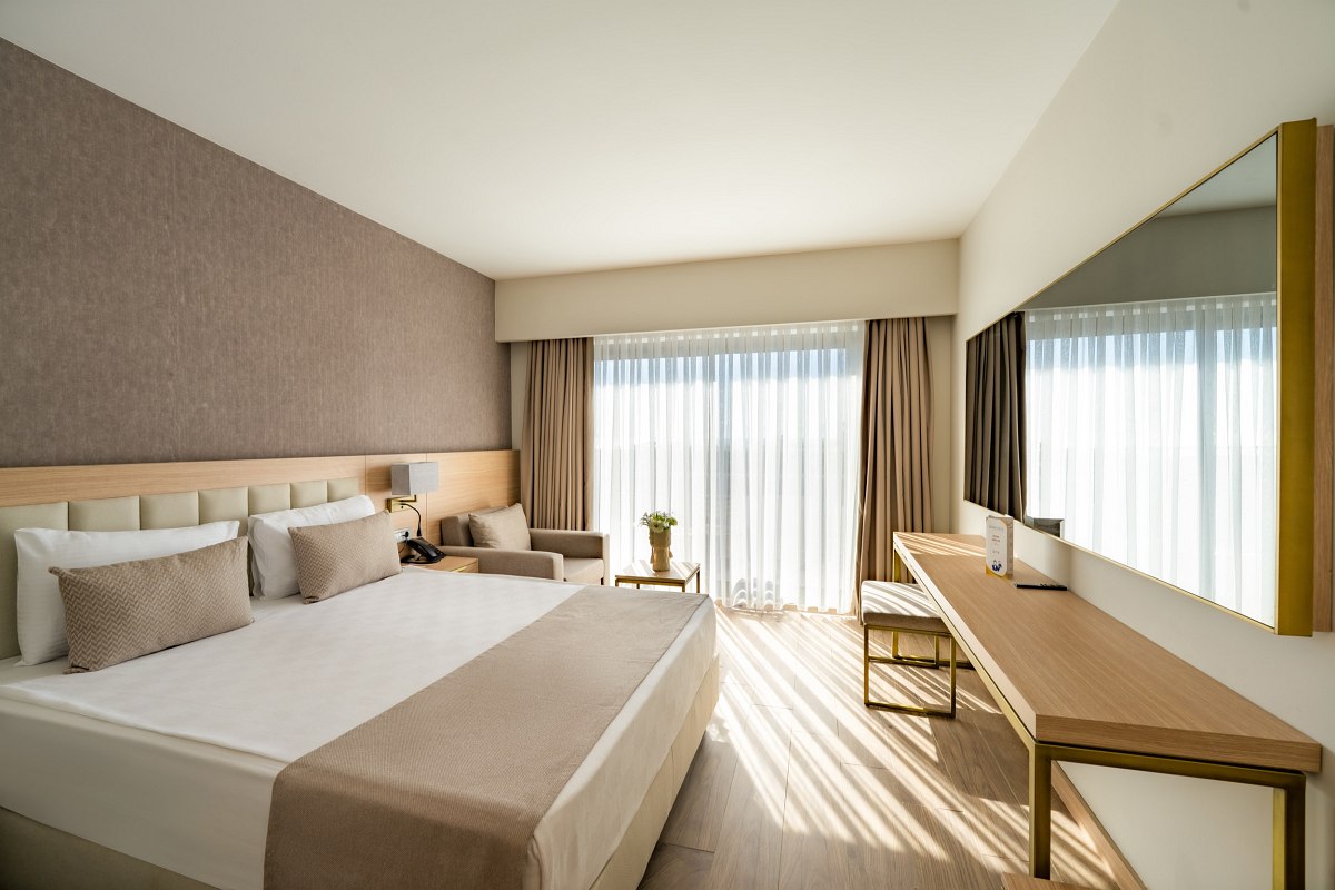 Modern double room with king-size bed, desk, flat-screen TV and cozy seating area.