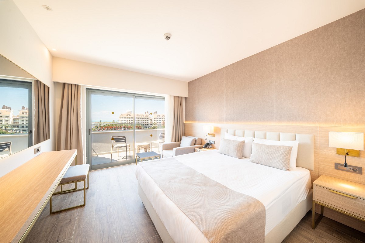 Elegant hotel room with two beds, stylish interior and balcony with fantastic sea view at dusk.