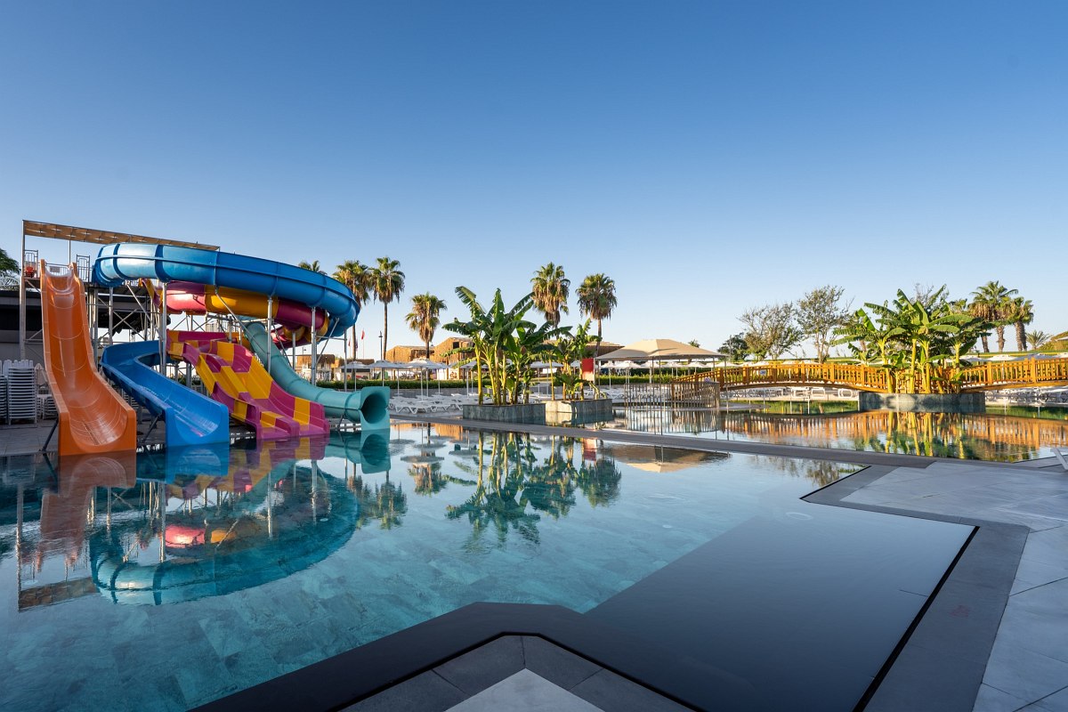 Luxurious beach cabana with thatched roof, white curtains and a view of the calm sea.