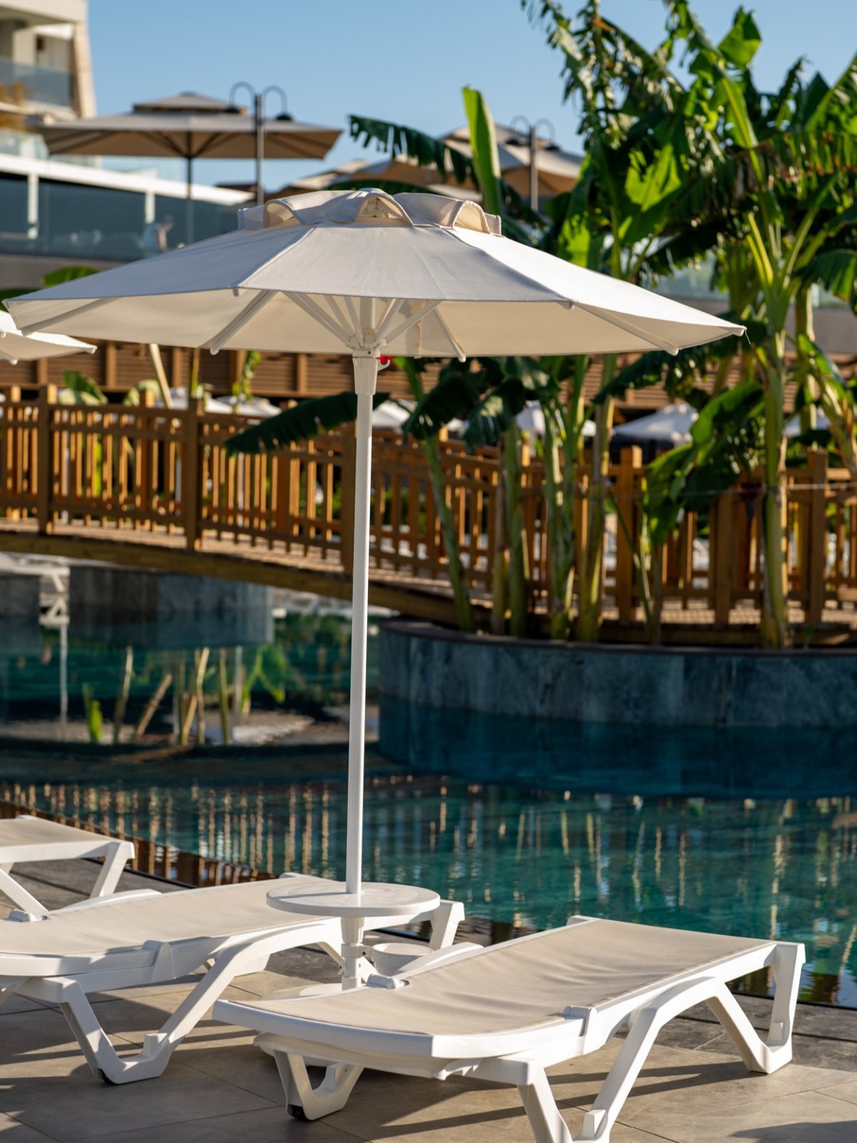 Magnificent hotel with a white façade and towers, surrounded by palm trees and yellow flowers.