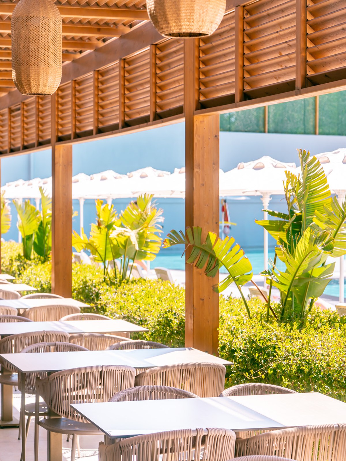 Magnificent hotel with a white façade and towers, surrounded by palm trees and yellow flowers.